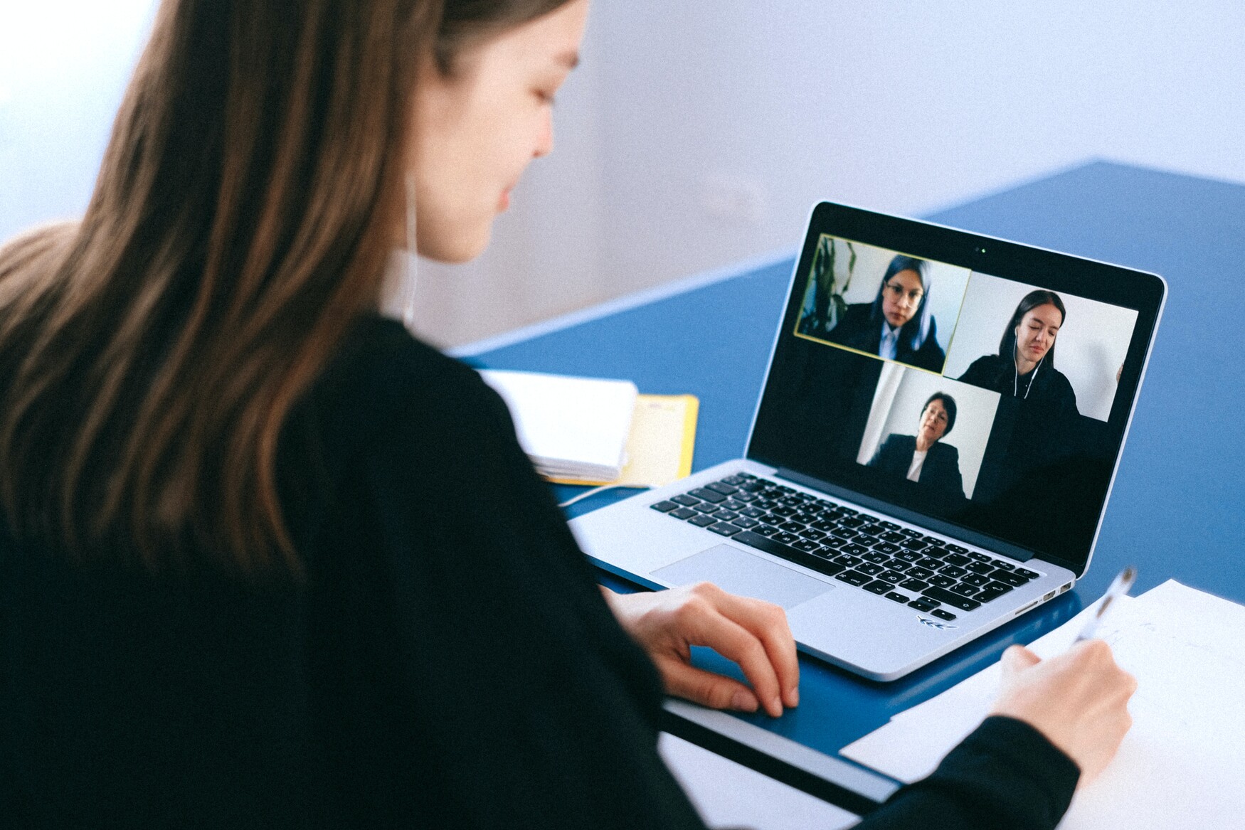 Woman chatting with three other women through a virtual meeting